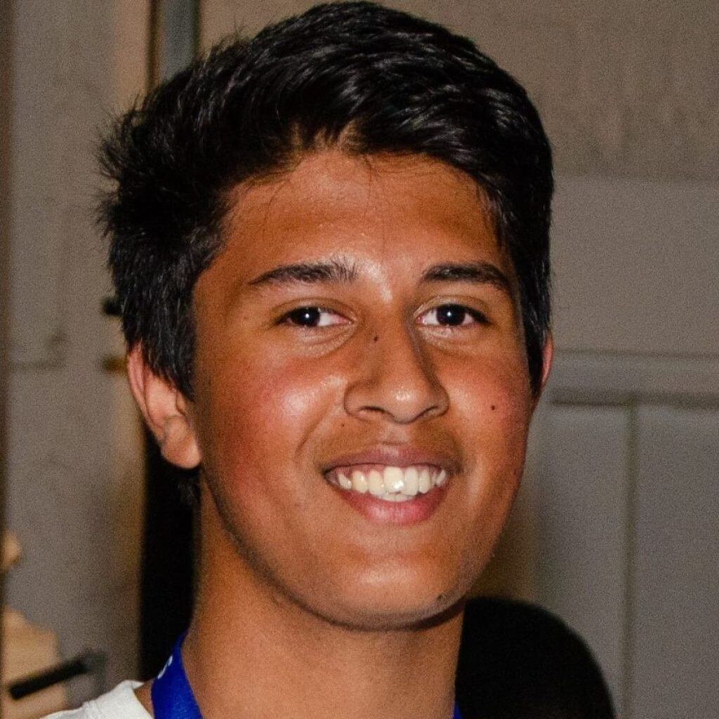 A boy wearing a white shirt with his arms crossed, smiling