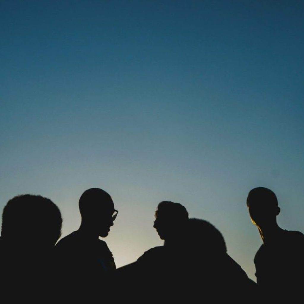 Multiple silhouettes of people against a blue sunset