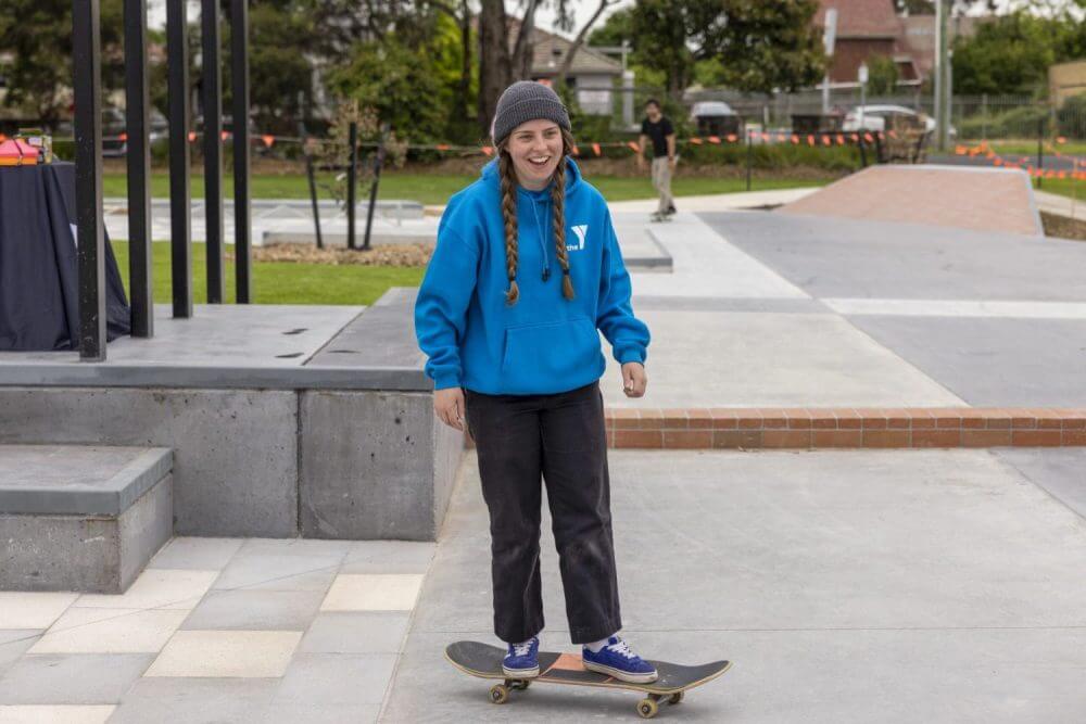 Person in a blue hoodie smiling on a skateboard