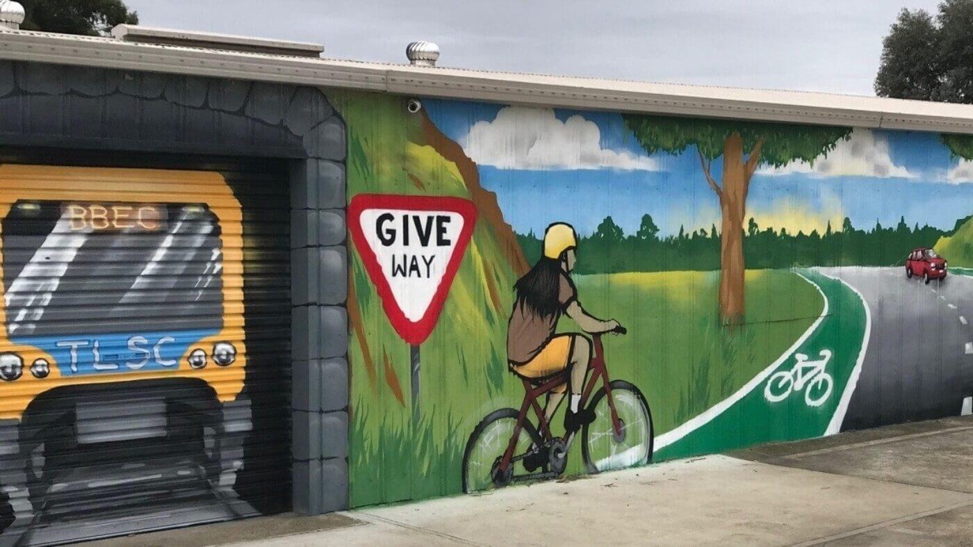A mural showing a bicycle riding along a road with the "Give Way" sign