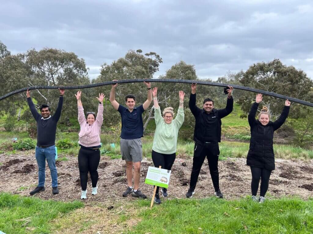A group of volunteers hold up a pipe at the park