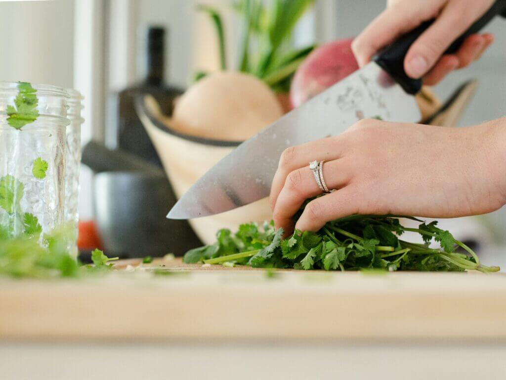 A close up of someone chopping a bunch of coriander