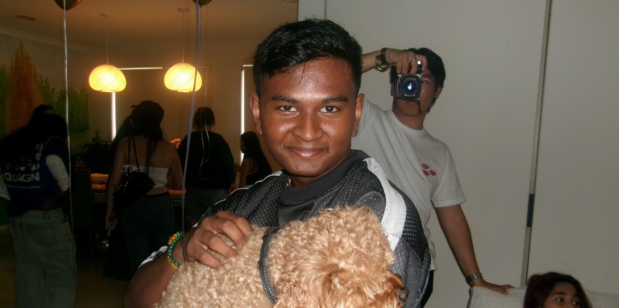 Yuwal smiles at the camera while holding a poodle
