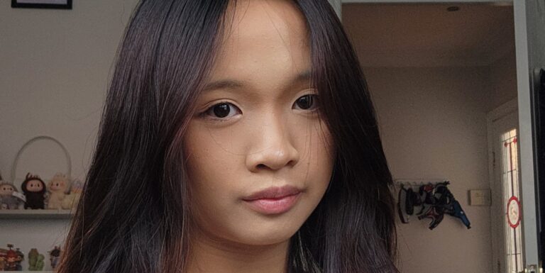 Aimi is staring directly into the camera. She has long dark brown hair