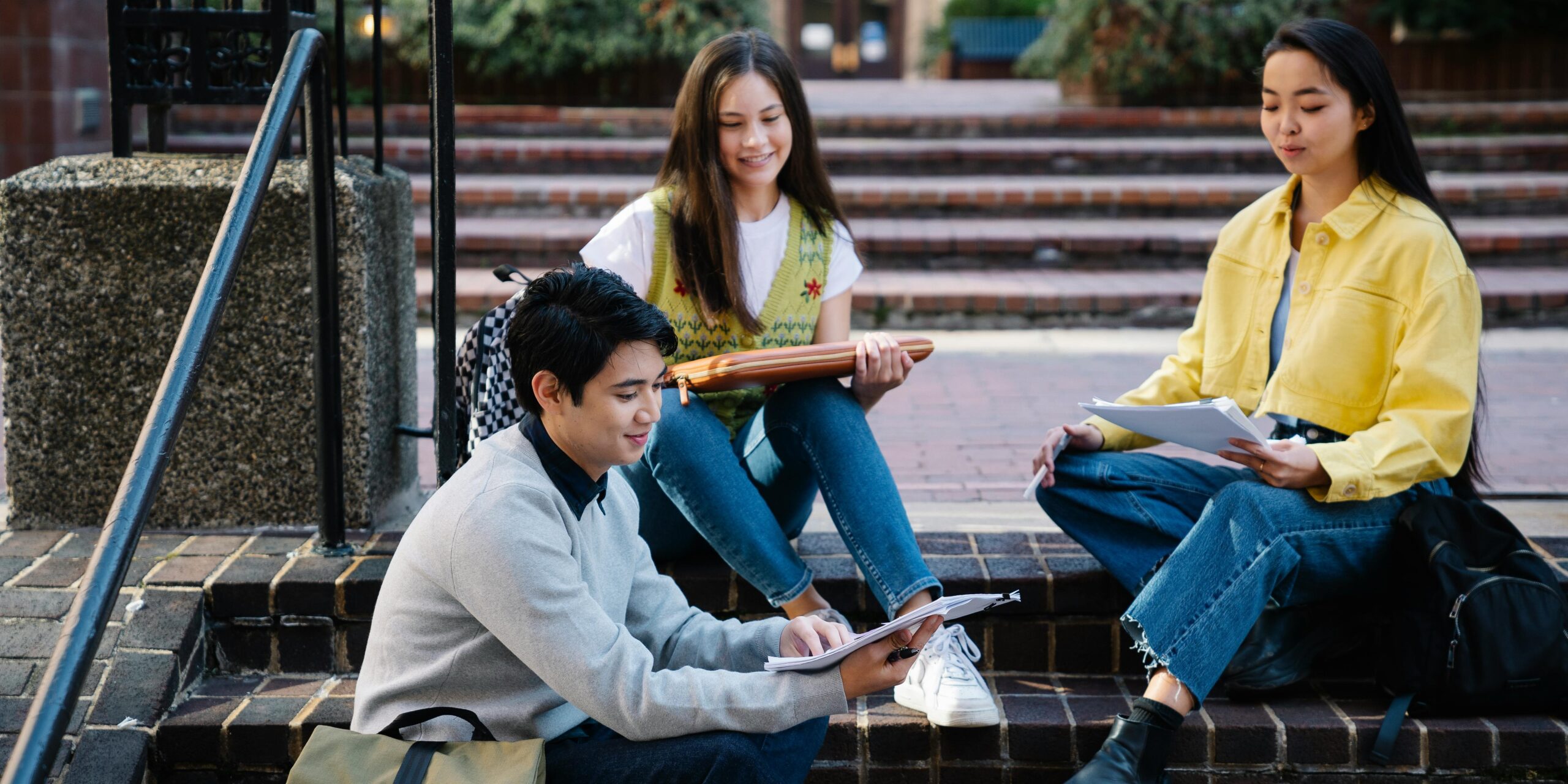 Group of young people sit on the stairs looking at books together