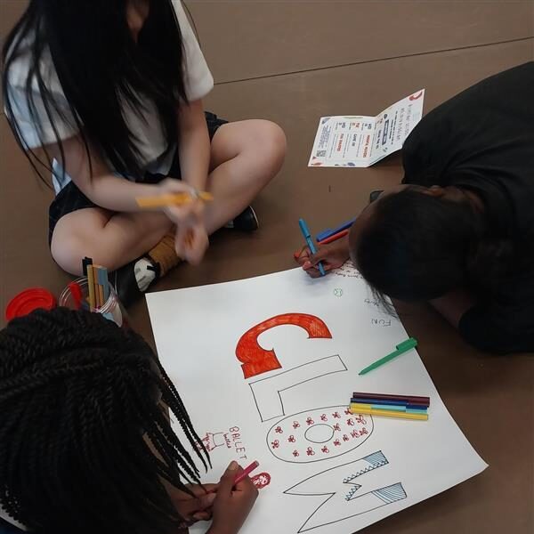 A group of three young people draw the word "GLOW" on paper