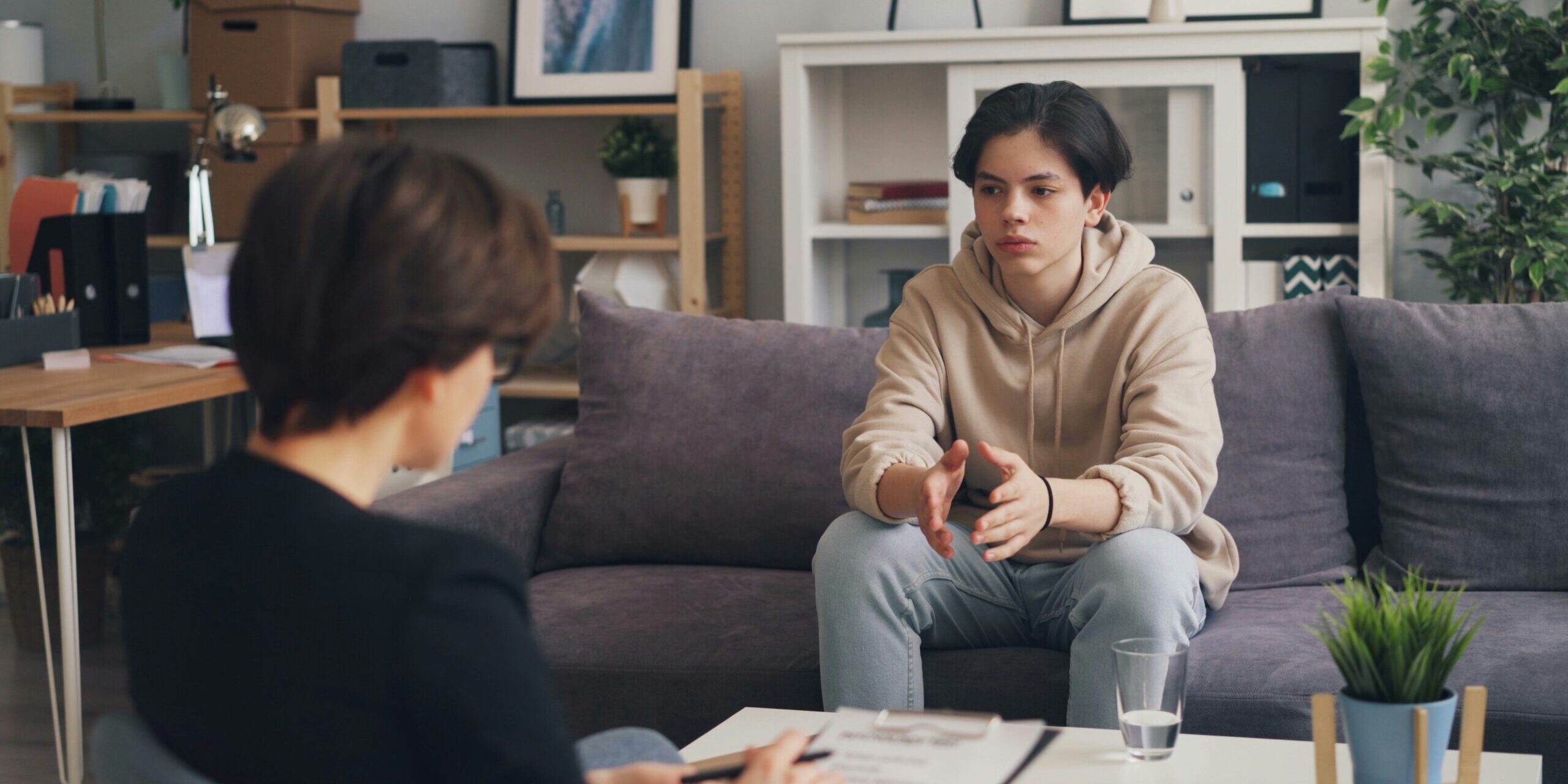 A young boy speaks to an adult while sitting on a couch