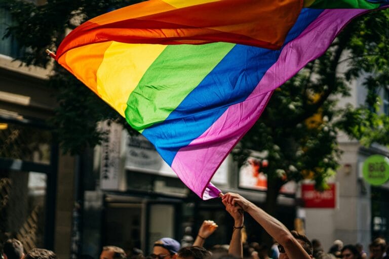 close up of a hand waving a rainbow flag