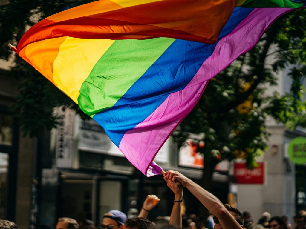 close up of a hand waving a rainbow flag