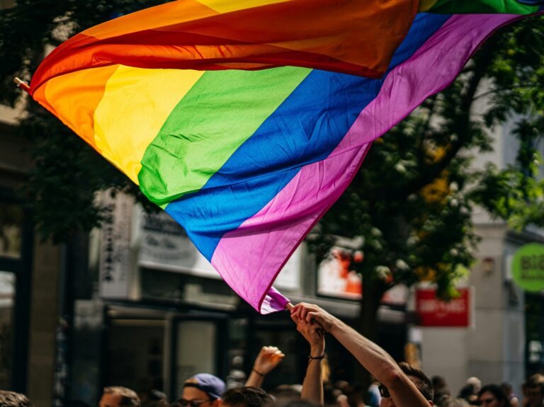 close up of a hand waving a rainbow flag